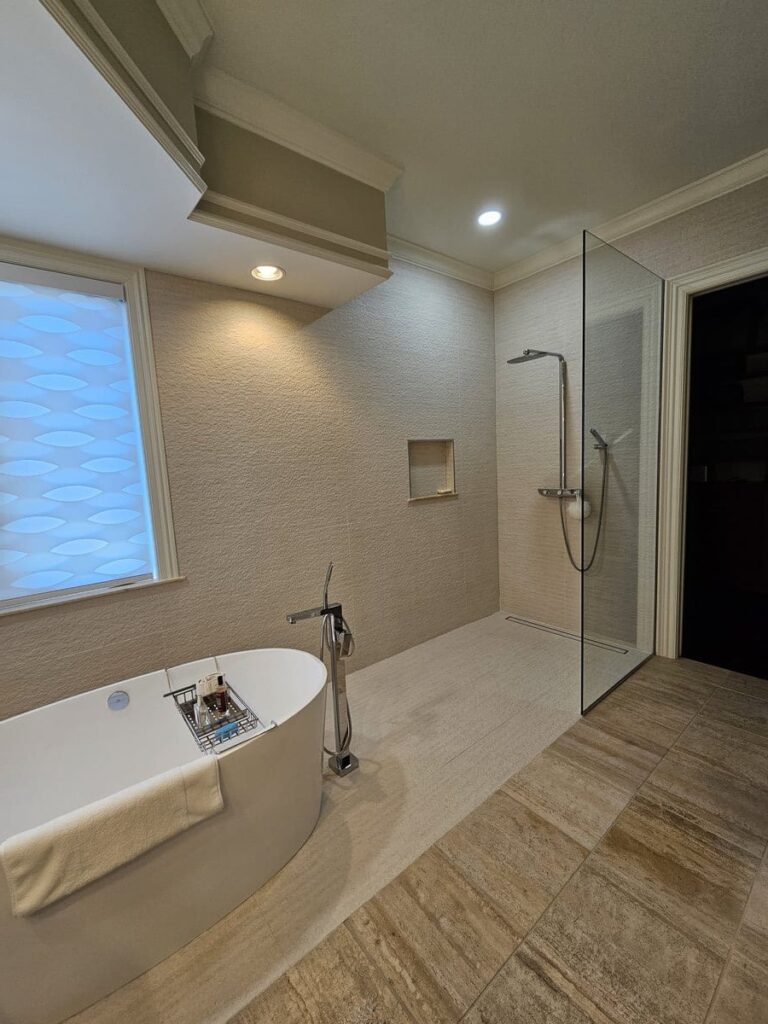 A doorless shower entery with a standalone tub from a custom bathroom project in Estero