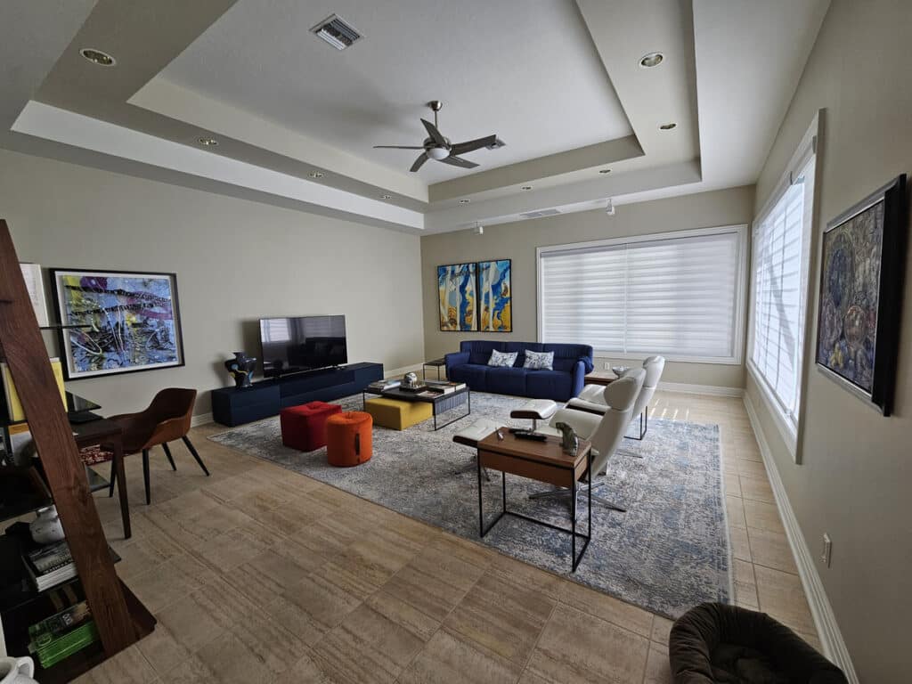 Living room renovation completed in Fort Myers with a blue couch a few chairs and a TV