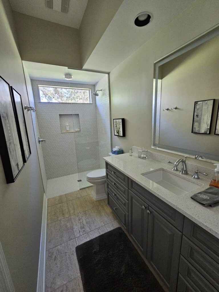 Restroom with a glass shower, grey oak, and white marble countertops in Cape Coral