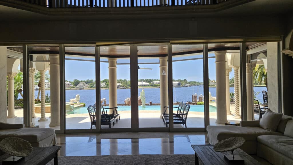 A living room view in a Sanibel home, overlooking the patio and pool with the ocean in the background 