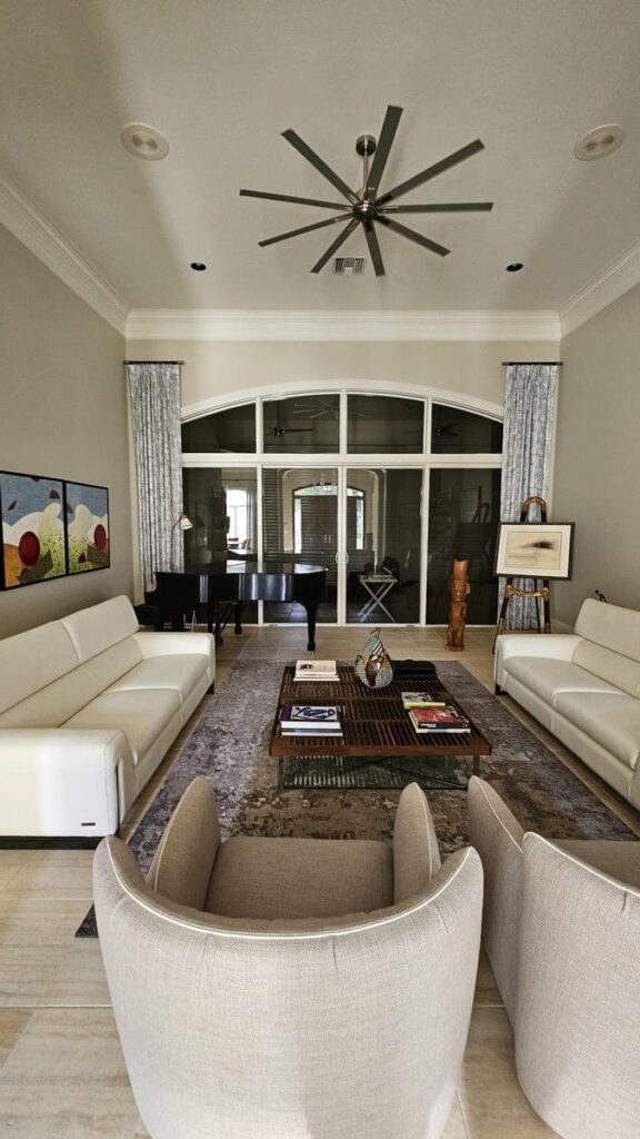 Narrow living room with white couches a large fan. All part of a home renovation in Marco Island